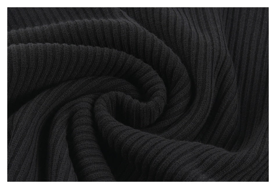 Black ribbed fabric gathered into a spiral fold, highlighting its texture and drape.