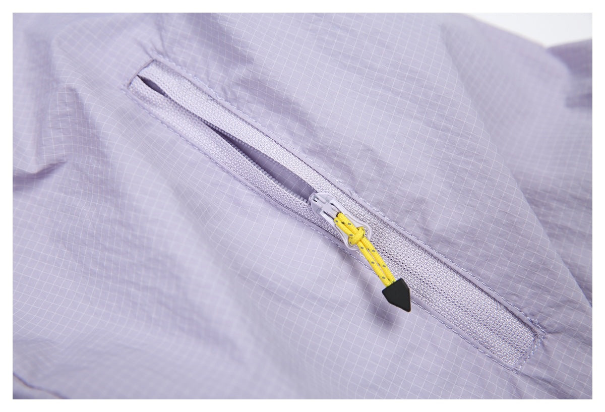 Close-up of a diagonal zipper on pale lavender grid-patterned fabric, with a yellow pull cord.