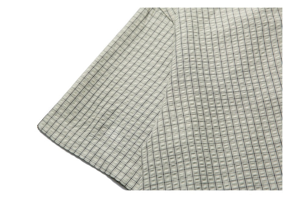 Cropped back view of a pale gray-green plaid shirt with short sleeves, laid flat.