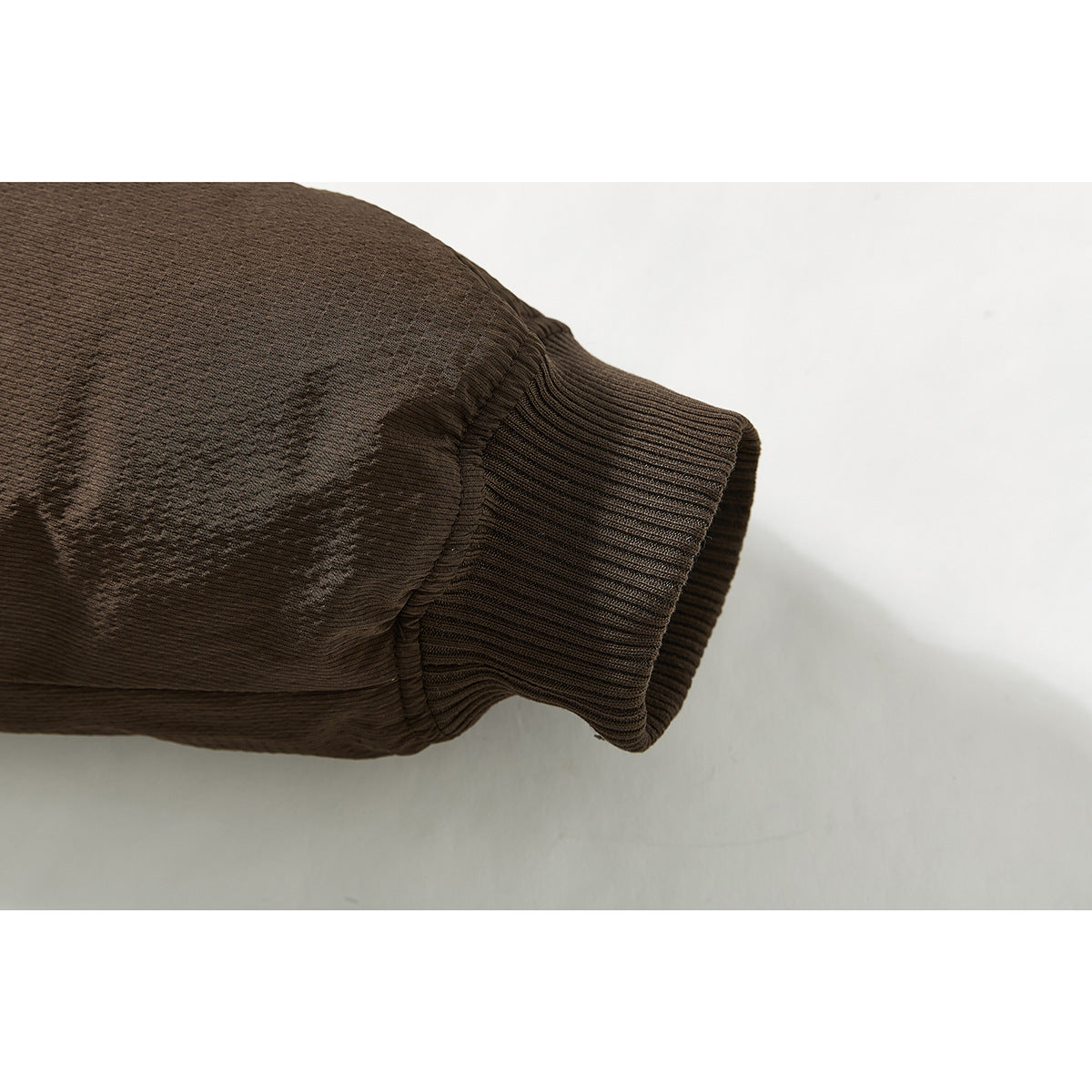 Close-up of a dark brown jacket sleeve ending in a ribbed cuff.