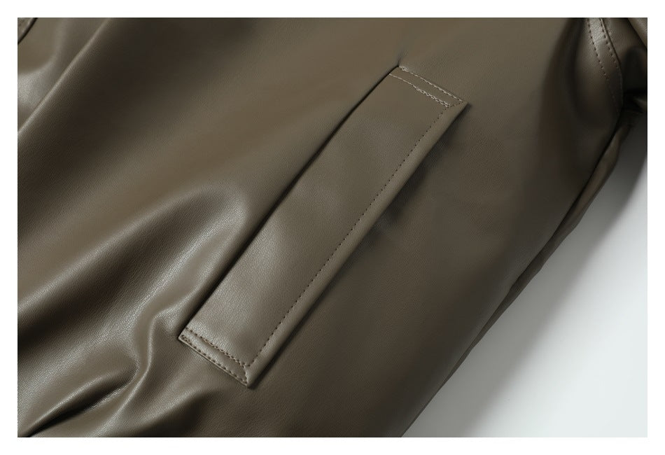 Close-up of a long rectangular pocket opening on the smooth olive-brown jacket.