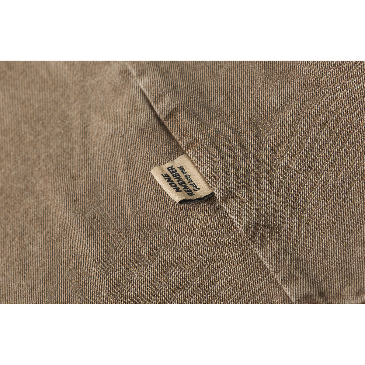 Close-up of a small label on brown textured shirt fabric.