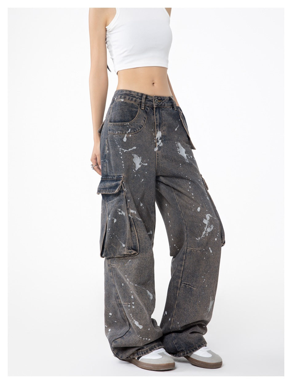 Model wearing loose charcoal-gray splatter-print cargo jeans with large side pockets, shown from a front three-quarter angle.