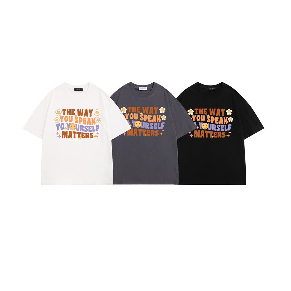 Three short-sleeve graphic T-shirts shown front-facing in white, charcoal gray, and black.