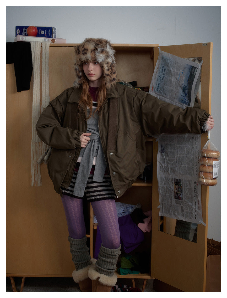 Model wearing an oversized olive-brown jacket with ribbed front panels and a spotted faux-fur trapper hat.