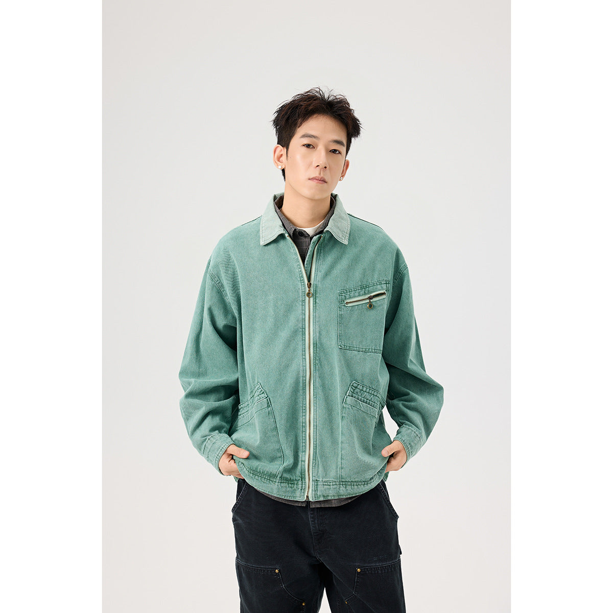 Model wearing a faded teal zip-front jacket with a chest zipper pocket and two angled lower pockets.
