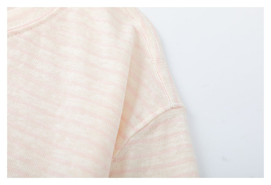 Close-up of a pale pink and cream striped knit garment showing a shoulder seam and sleeve.
