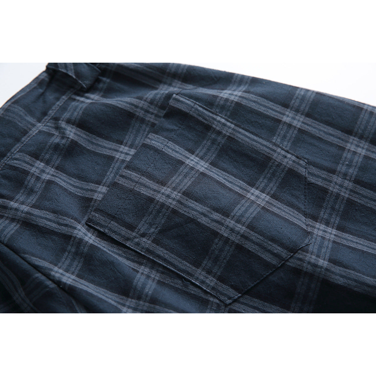 Close-up of a patch pocket on navy plaid shorts.