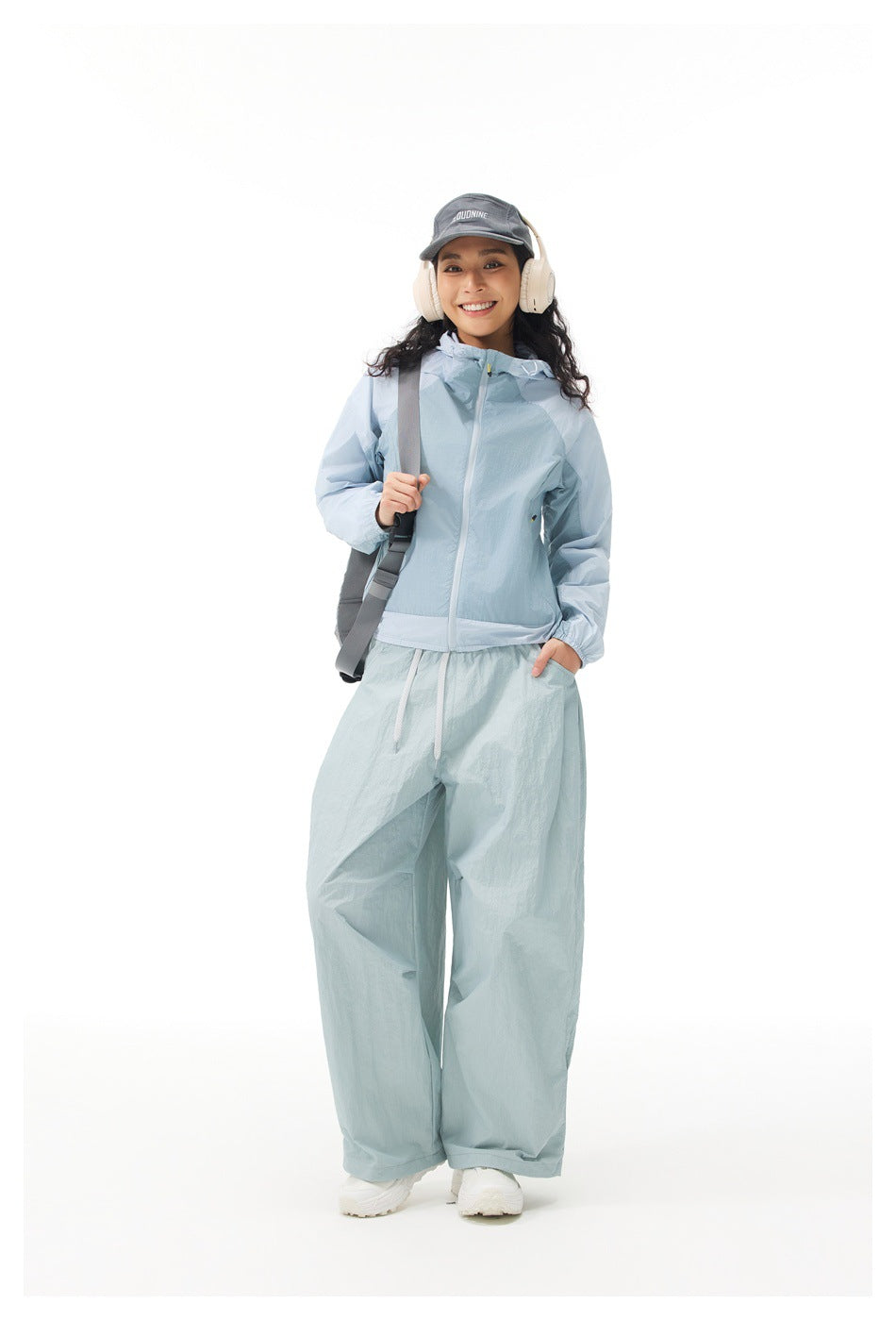 Full-length view of a model in a light blue hooded zip jacket and loose pale blue drawstring pants.