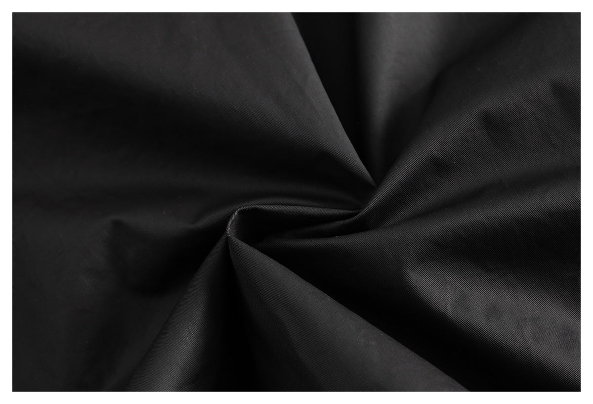 Close-up of black fabric gathered into folds, showing its fine diagonal surface texture.