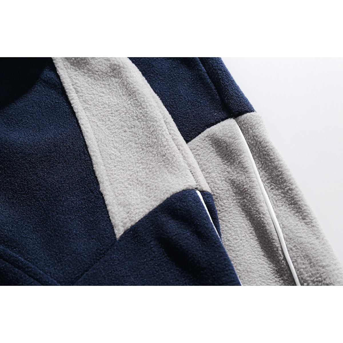Close-up of the navy and light-gray color-block panels and seam on a fleece top.
