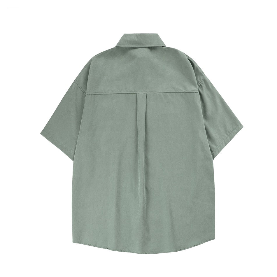 Back view of a muted sage-green short-sleeve button-up shirt with a pointed collar and center back pleat.