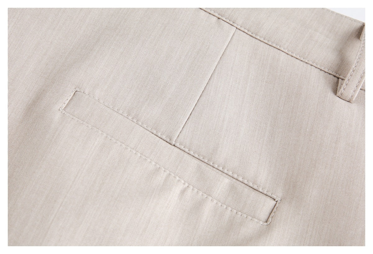Close-up of a stitched welt pocket and belt loop on the back of beige trousers.