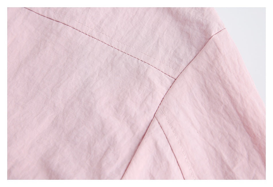Close-up of pale pink jacket fabric showing stitched panel seams.