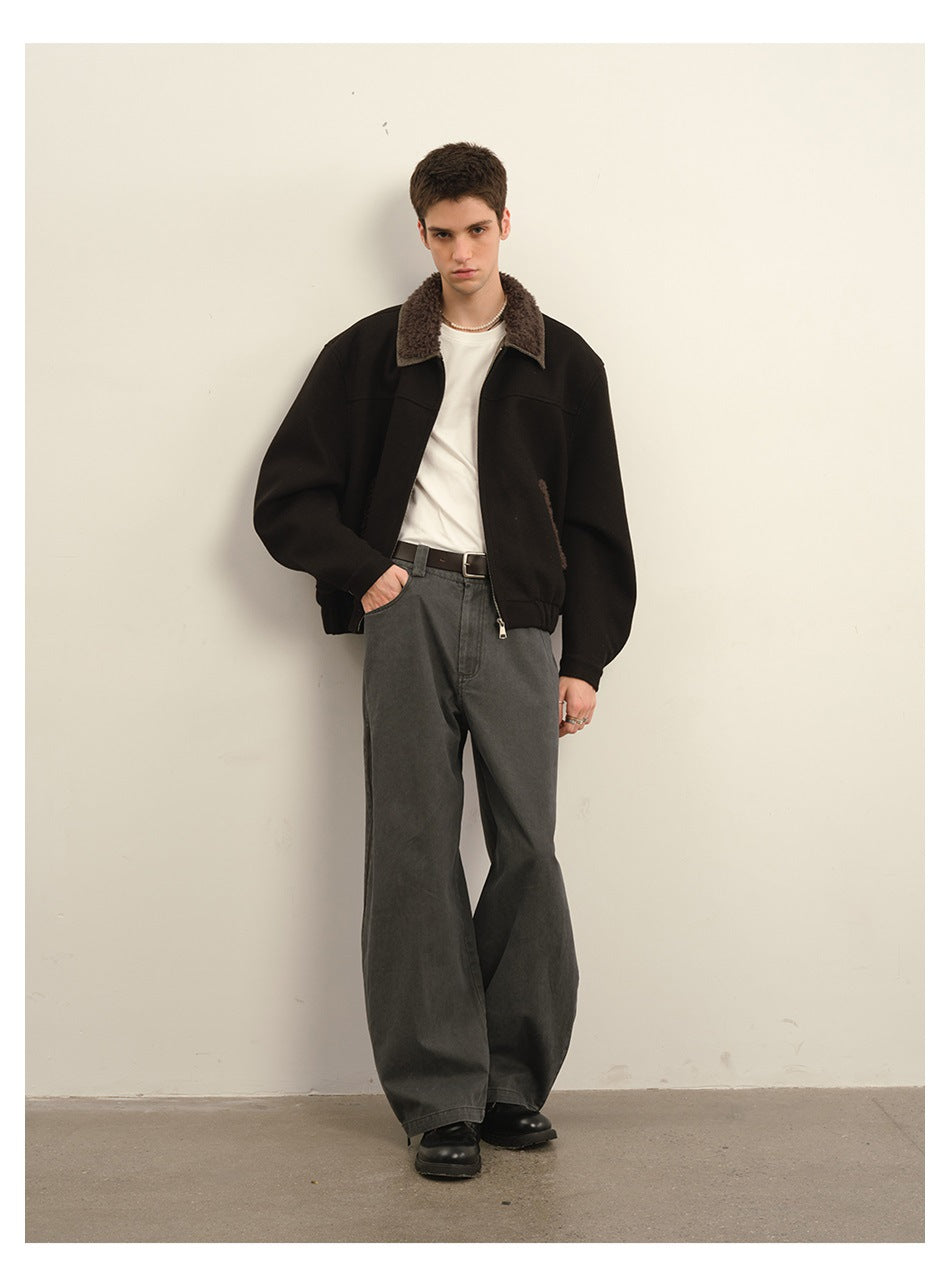 Front view of a model wearing a black zip jacket with a brown textured collar and pocket trim, white shirt and charcoal