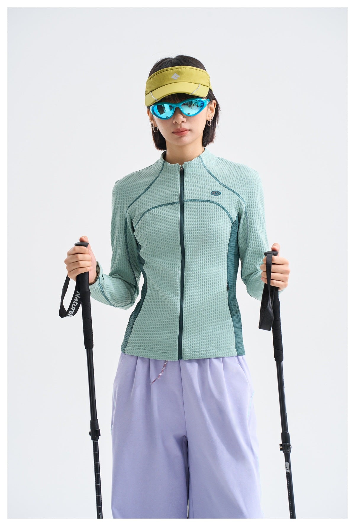 Model wearing a pale aqua textured zip-front jacket with dark teal curved seams and side panels.