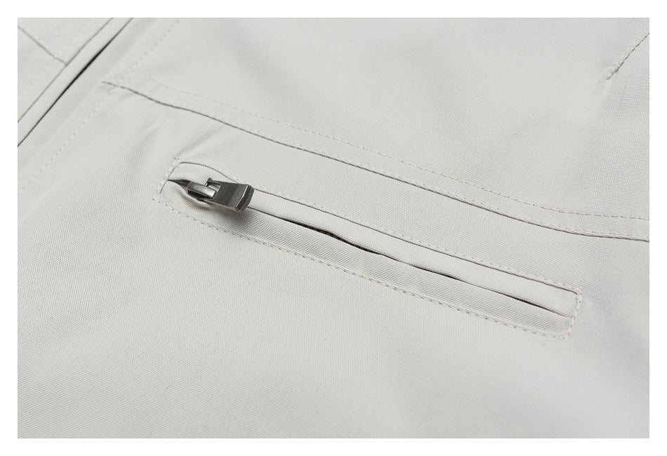 Close-up of a light gray jacket's horizontal zip pocket and stitching.