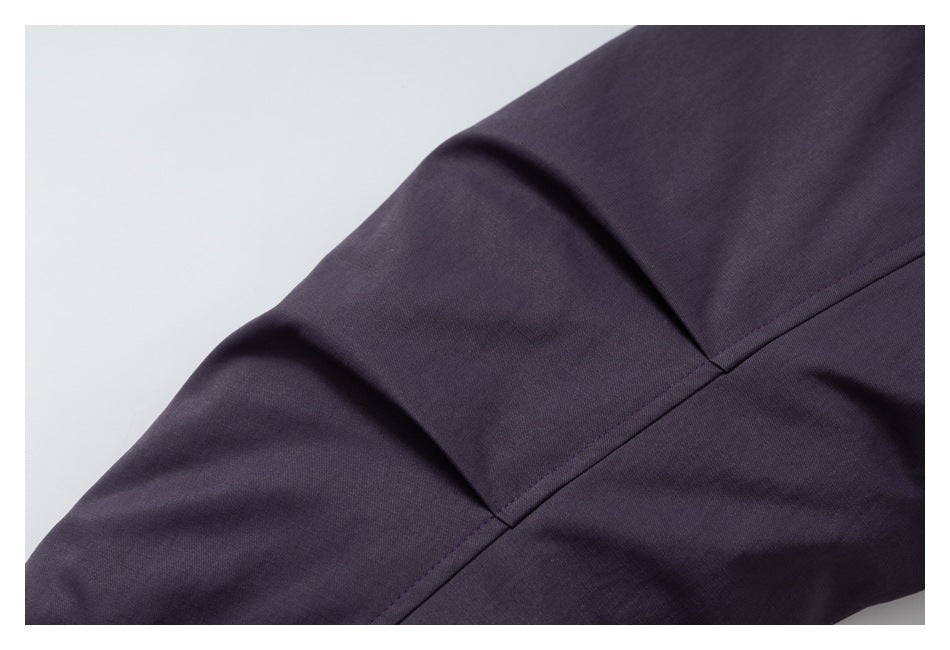 Close-up of a dark purple coat sleeve showing its seam and stitched panel.