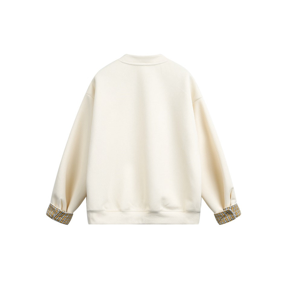 Back view of a cream button-front jacket with long sleeves, a ribbed hem, and plaid turn-back cuffs.