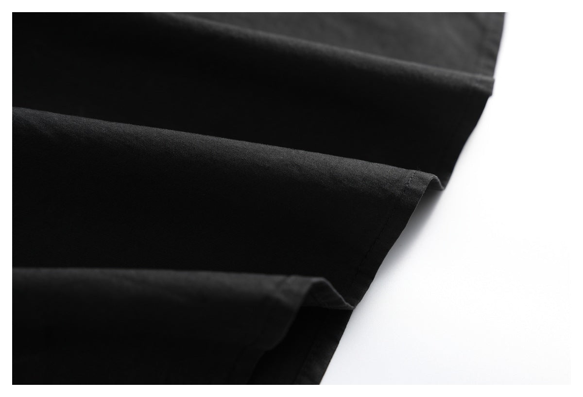 Close-up of a black garment's folded, stitched edge against a white background.