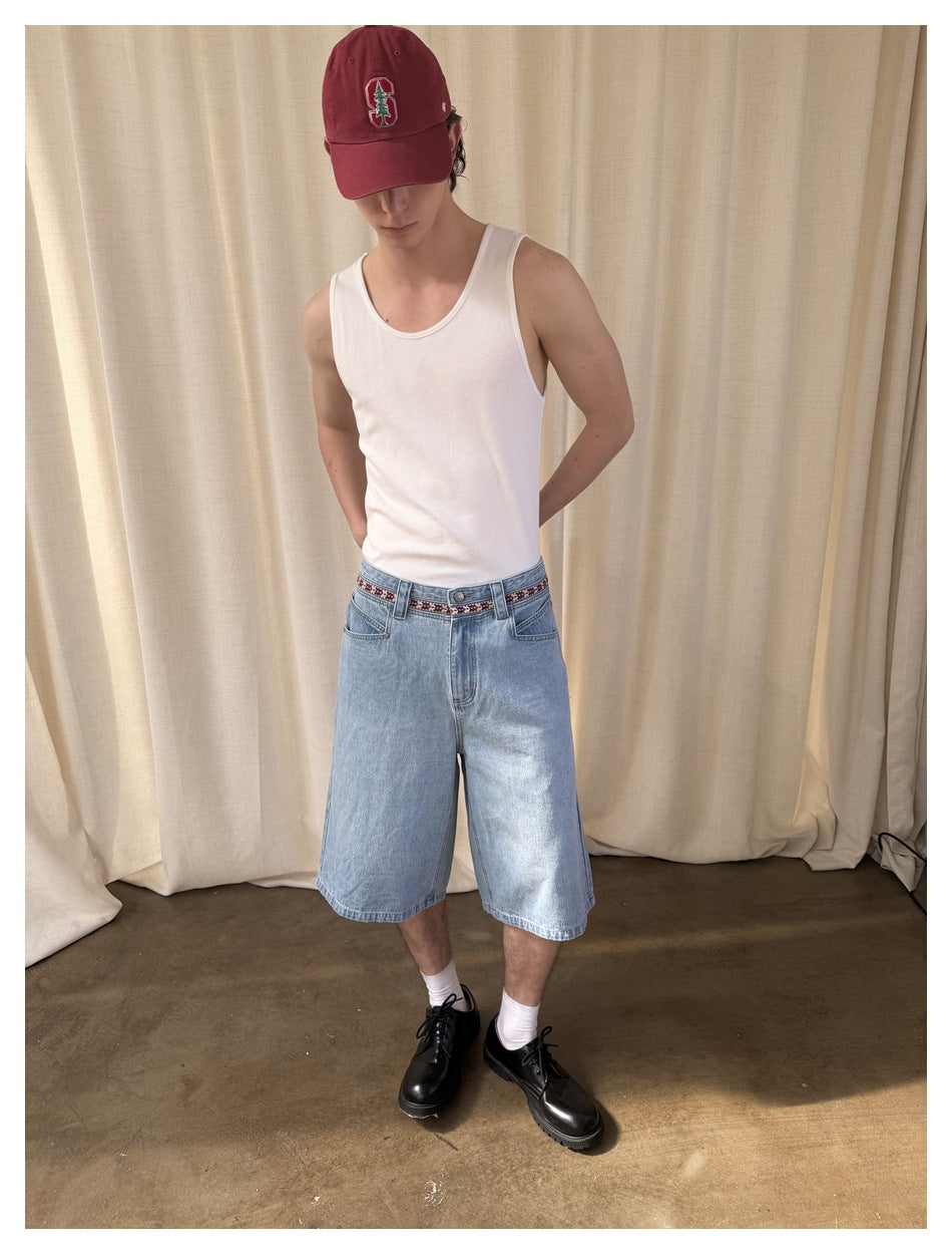 Model wearing light-wash, wide-leg denim shorts with a patterned waistband, shown from the front in a three-quarter pose.