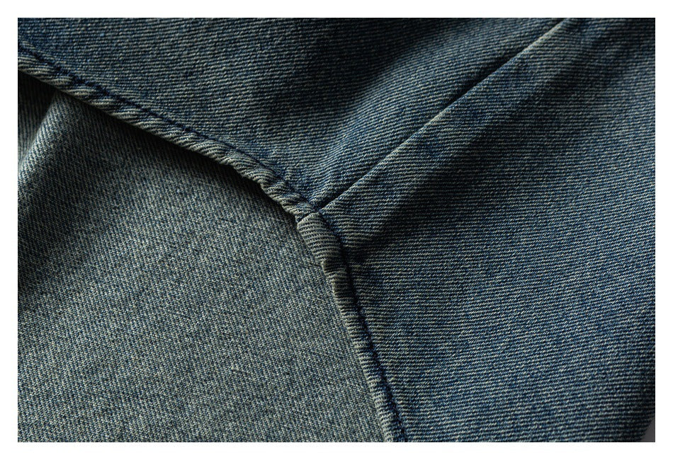 Close-up of blue denim showing a curved stitched seam meeting a vertical seam.