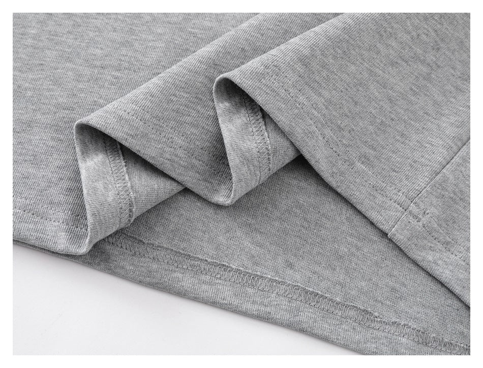 Close-up of a heather-gray garment hem, showing folded fabric and stitching.