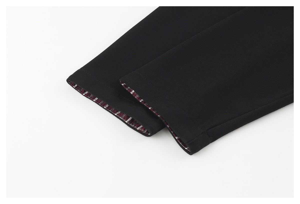 Close-up of two black garment edges with burgundy plaid trim visible inside.