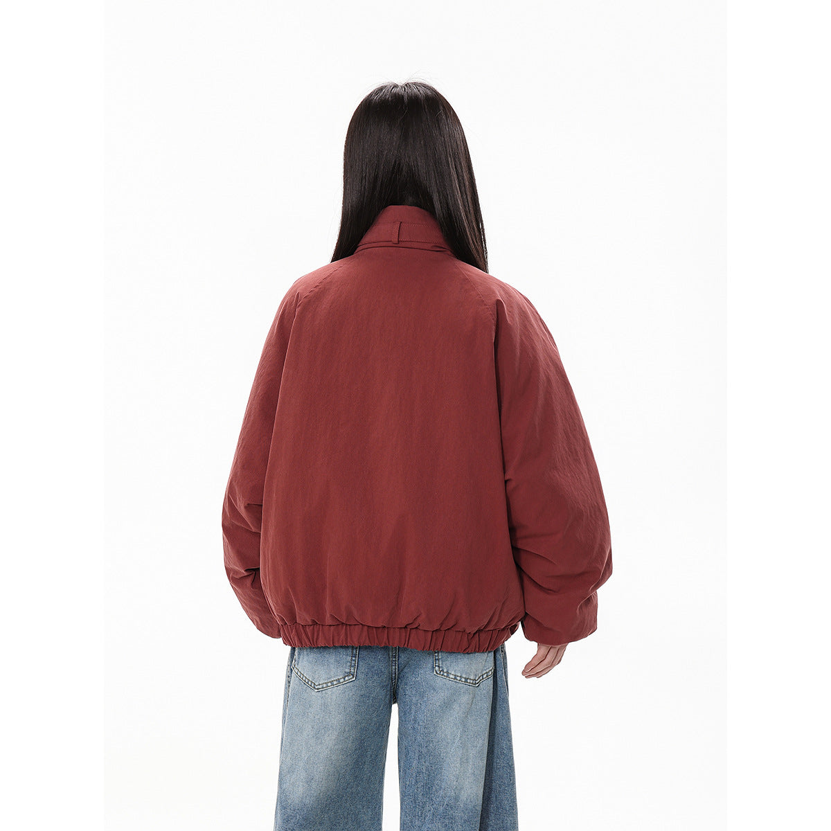 Rear view of the rust-red jacket on a model, showing its plain back and gathered elastic hem.