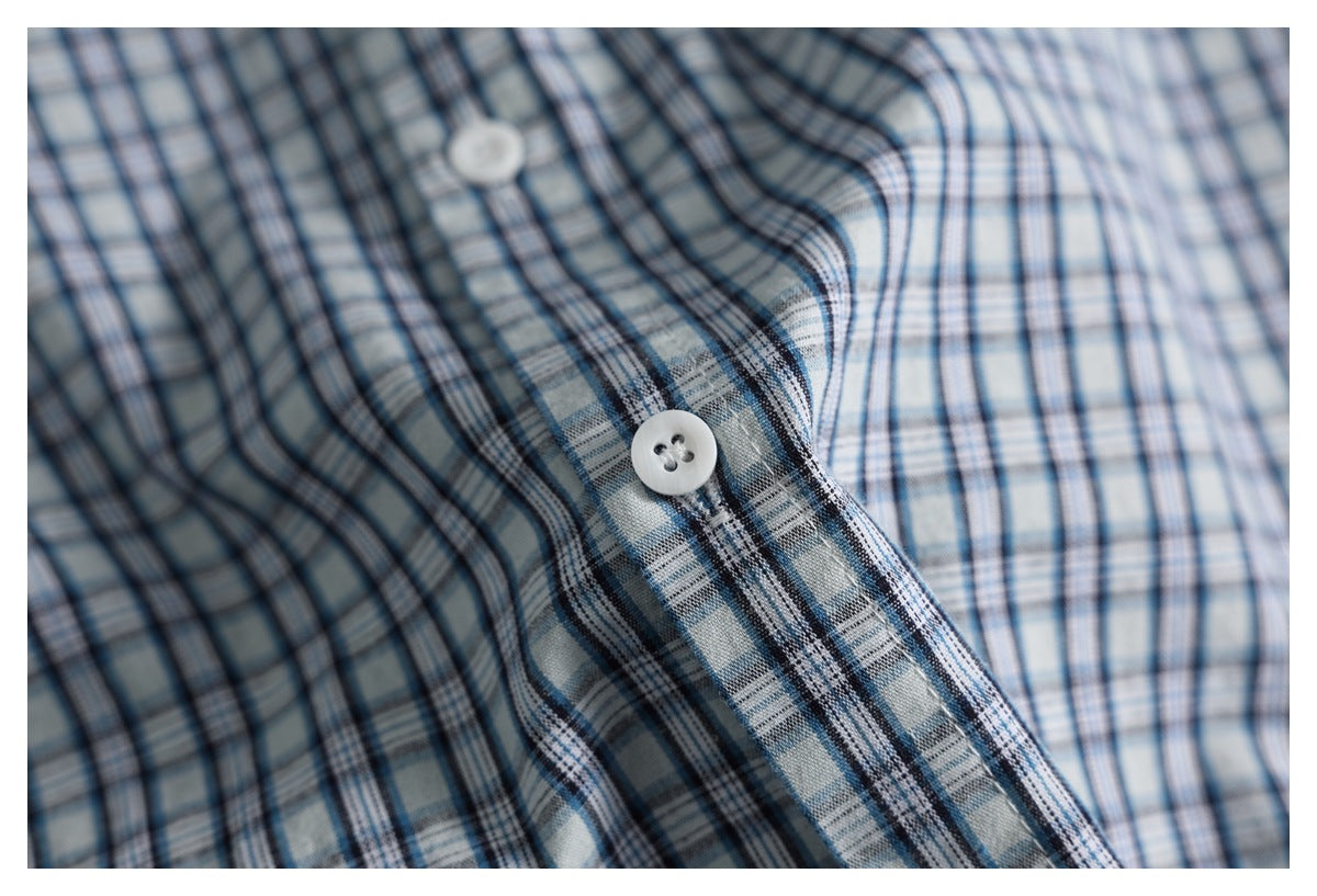 Close-up of the blue plaid shirt's white buttons and button placket.