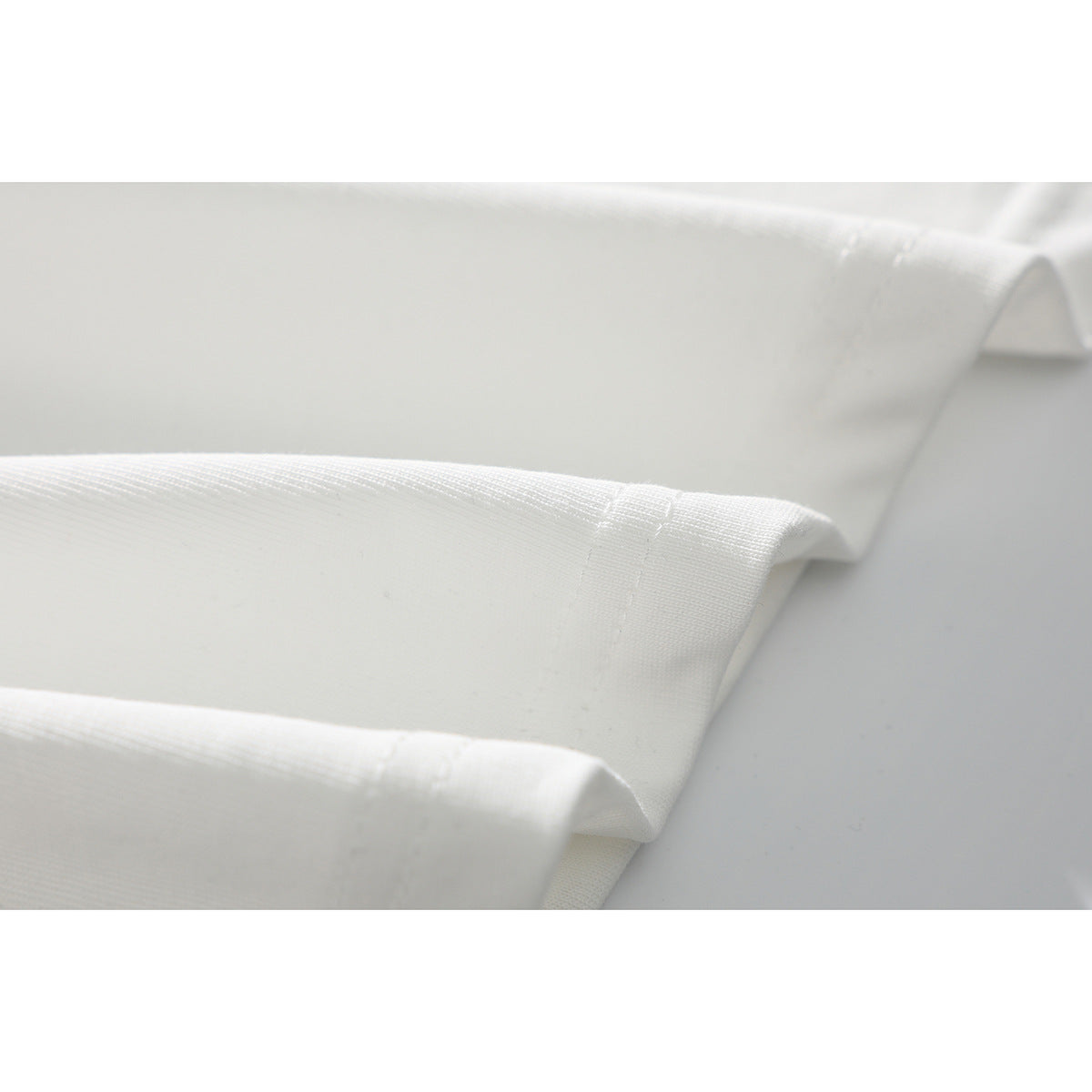 Close-up of the hemmed edge and knit fabric of a white T-shirt.