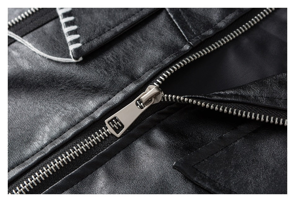 Close-up of a black jacket with a silver zipper, metal pull, and contrasting white stitching.
