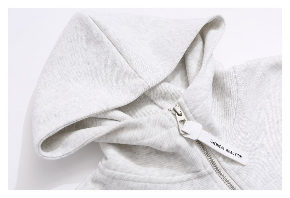 Close-up of a light gray hoodie hood and silver quarter-zipper with a white “CHEMICAL REACTION” pull tab.