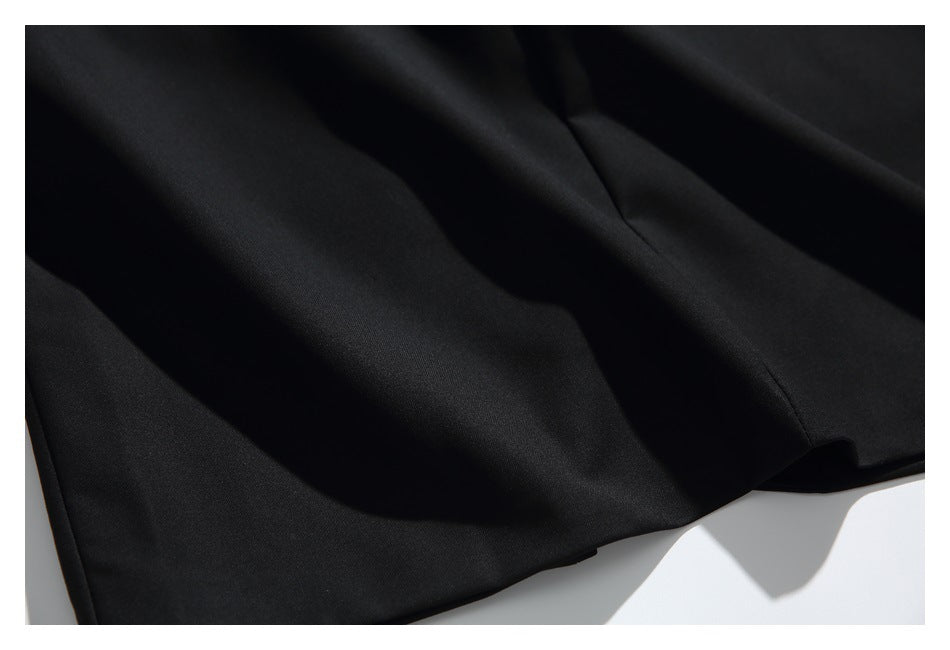 Close-up of the black garment's draped fabric and stitched seam.