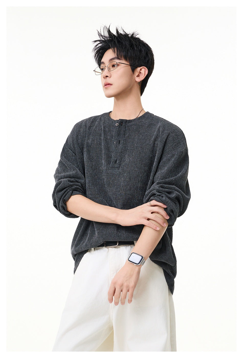 Model wearing a dark gray textured long-sleeve Henley-style pullover with white wide pants, arms crossed