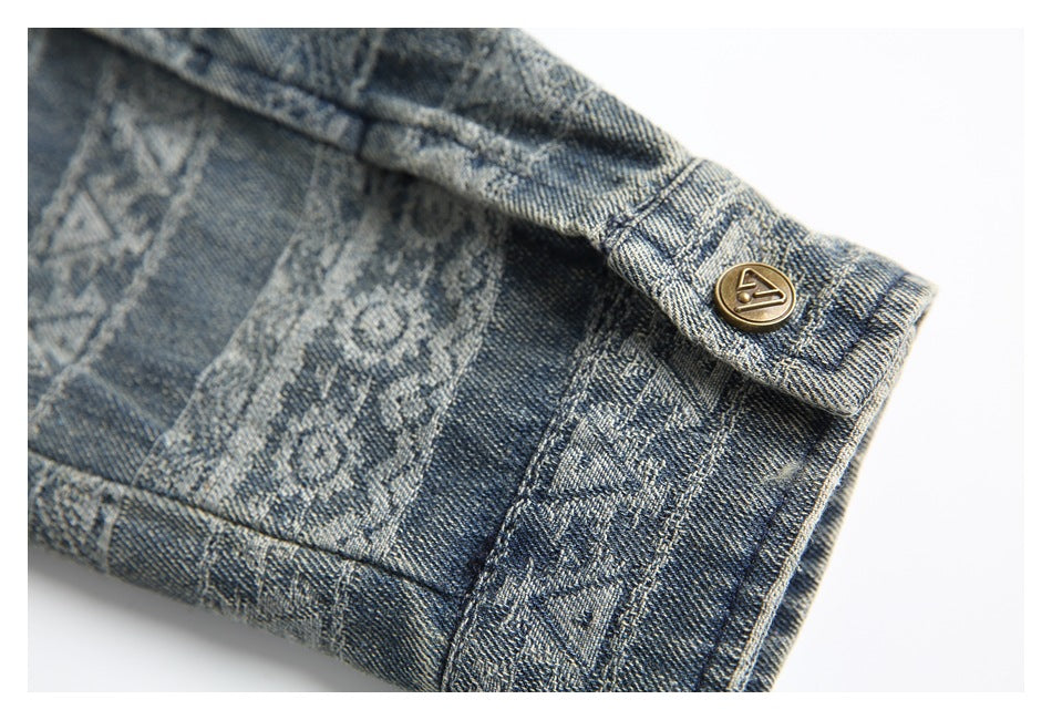 Close-up of a buttoned cuff on blue denim with geometric and floral patterns.