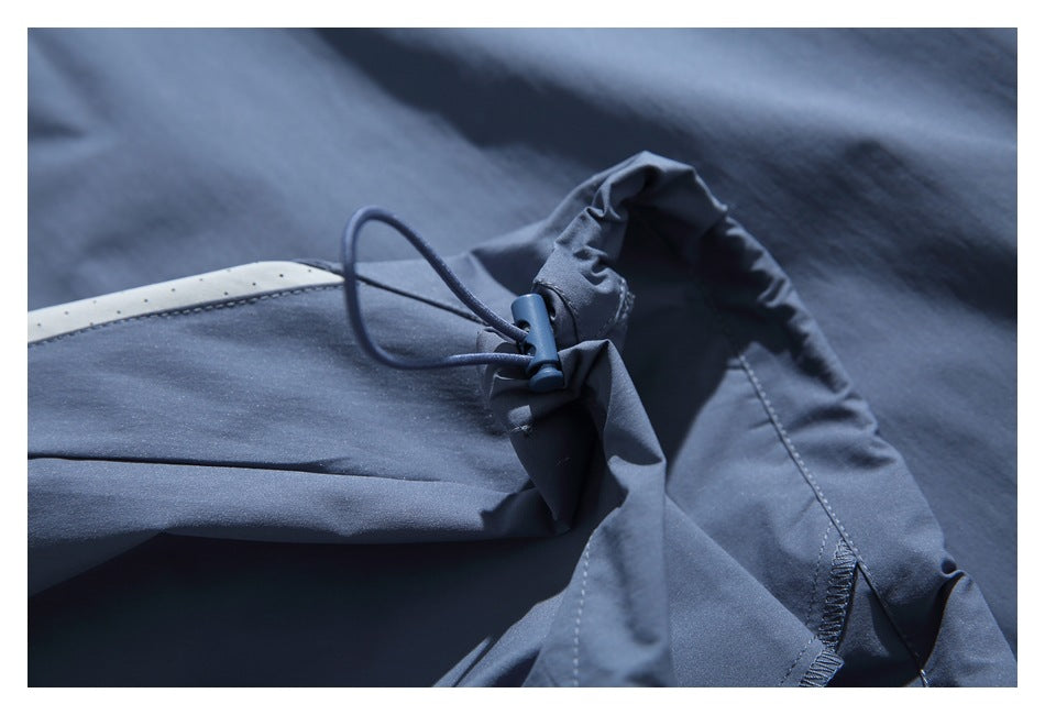 Close-up of a blue garment with an adjustable drawcord and toggle at a gathered seam.