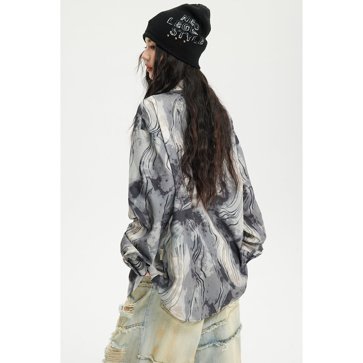 Rear view of a model wearing a gray and cream abstract-print shirt with a rounded hem.