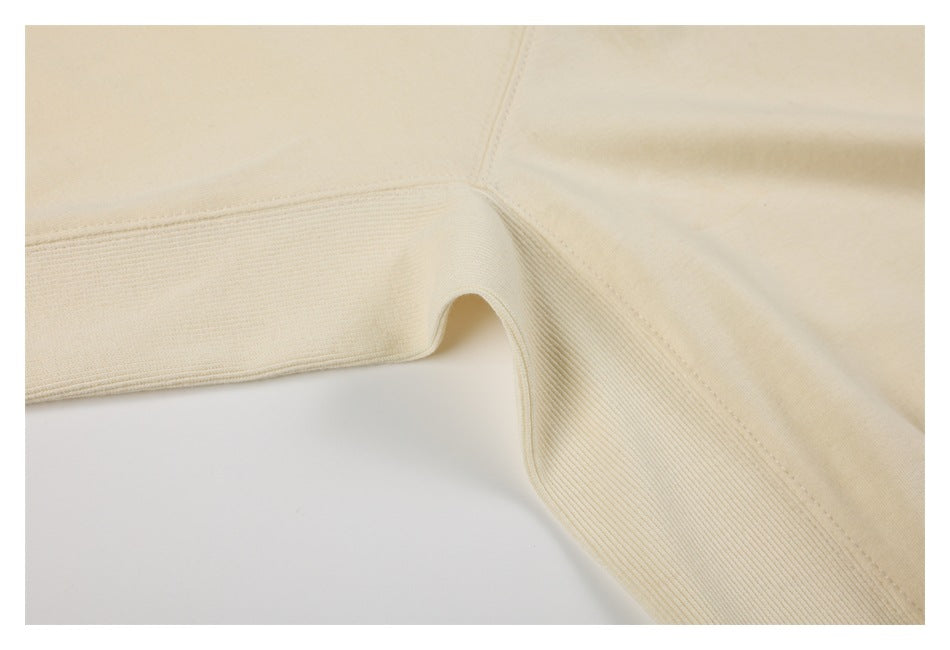 Close-up of an ivory sweatshirt’s underarm seam and wide ribbed side panel.