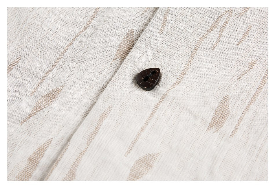 Close-up of a dark button on cream fabric with a tan abstract pattern.