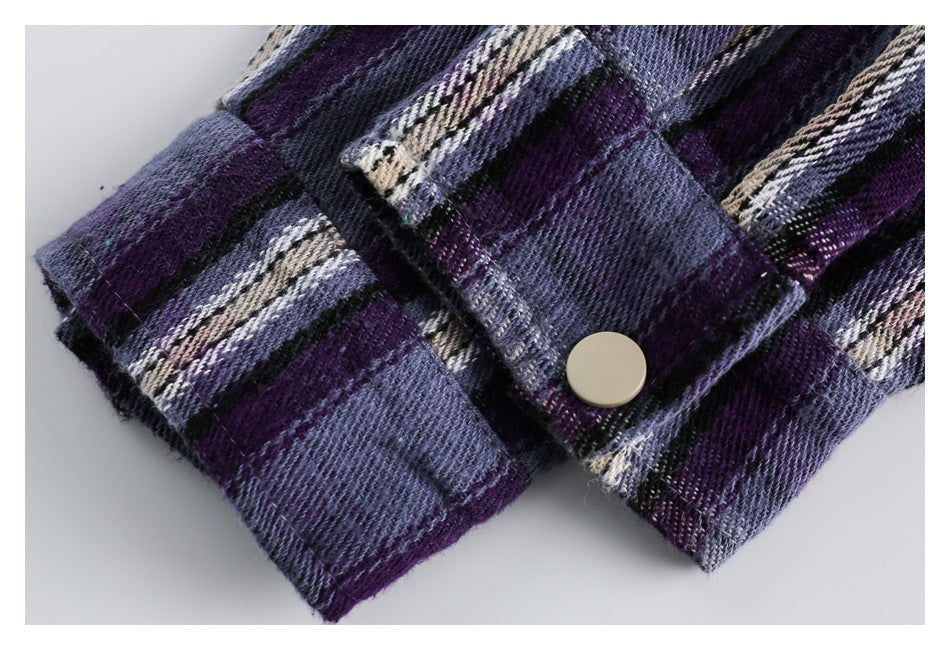Close-up of a plaid shirt cuff with a cream snap button, in purple, blue, black, and cream.