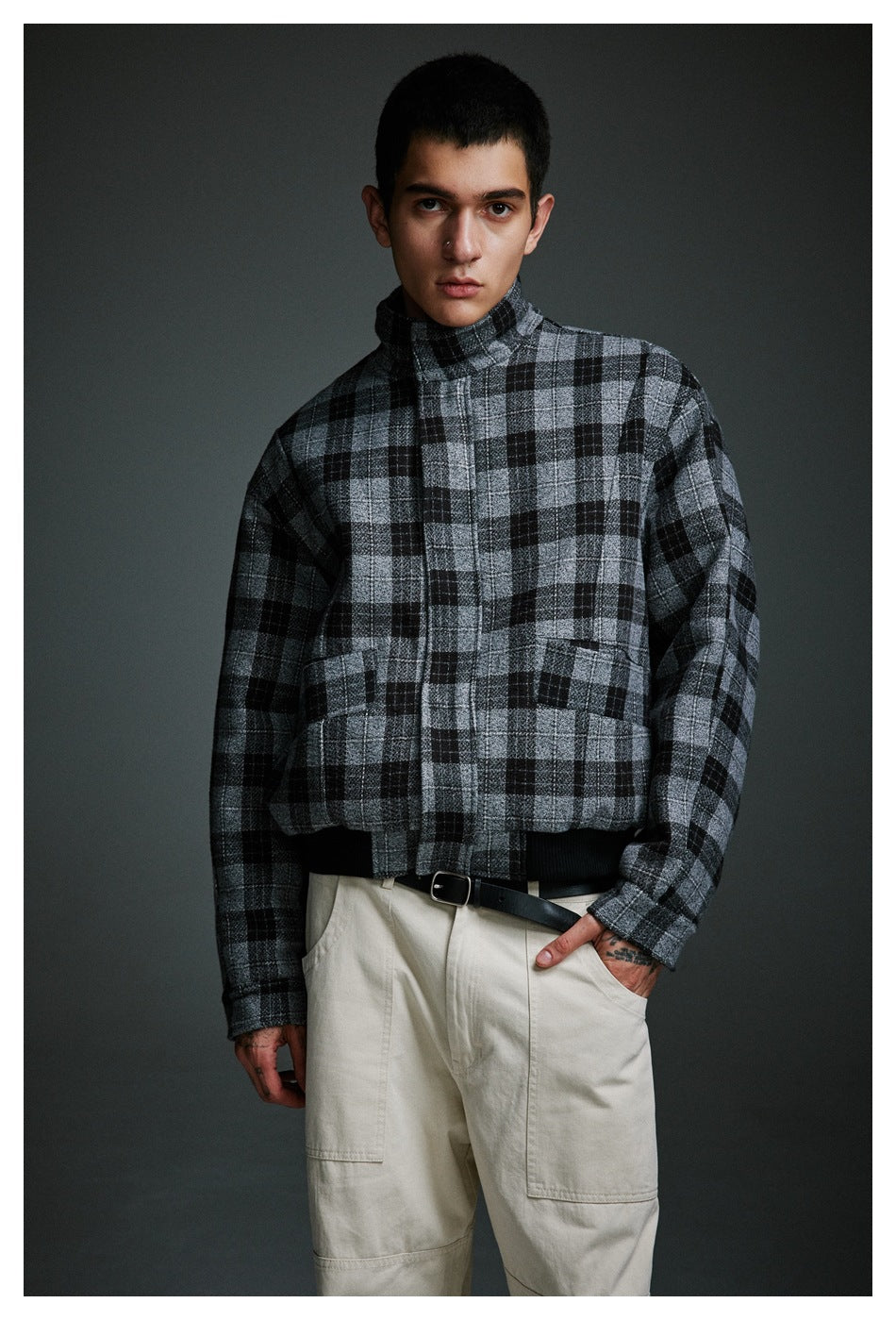 Front view of a man wearing a gray and black plaid high-collar jacket with two front pockets.