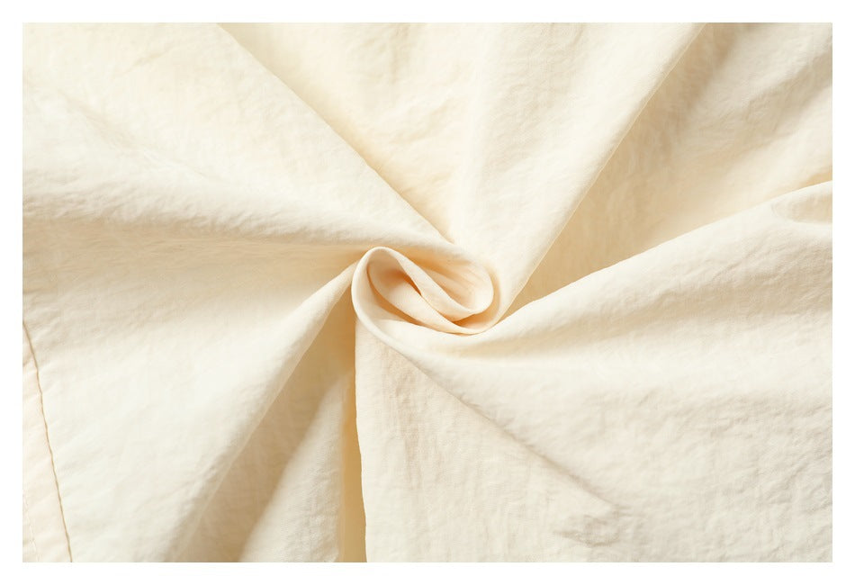 Cream fabric gathered into a soft spiral, with folds and surface texture visible.