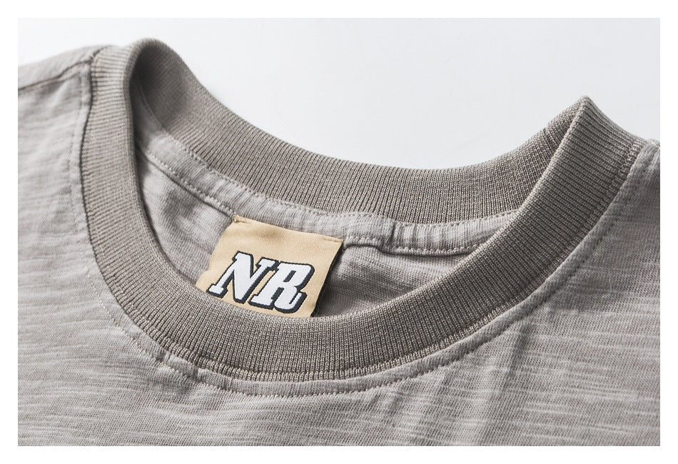 Close-up of a gray marled T-shirt's ribbed crew neckline and sewn NB neck label.