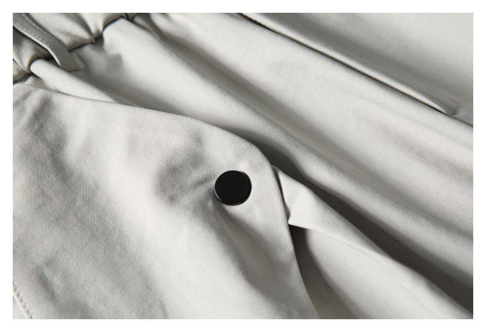 Close-up of a black button on a light gray trouser pocket flap.