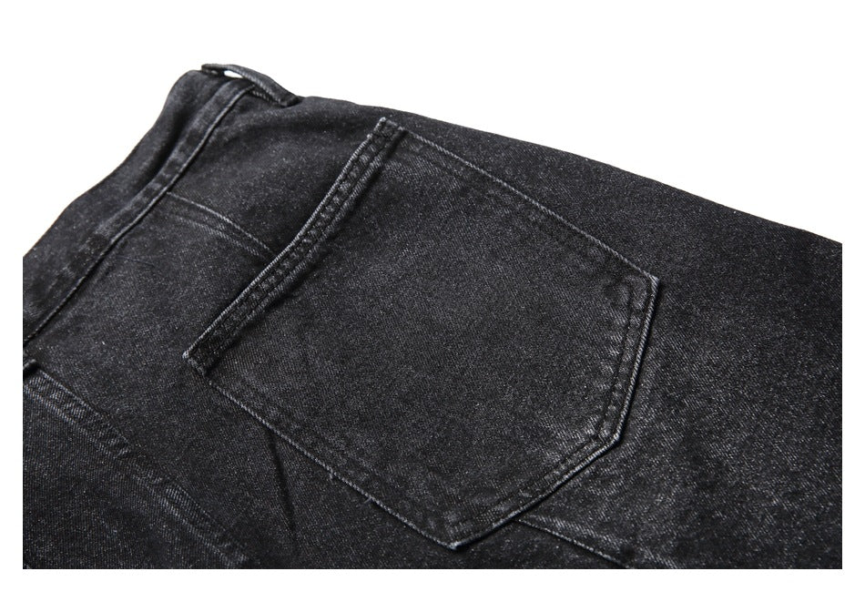 Close-up of a plain back pocket and seams on black denim shorts.