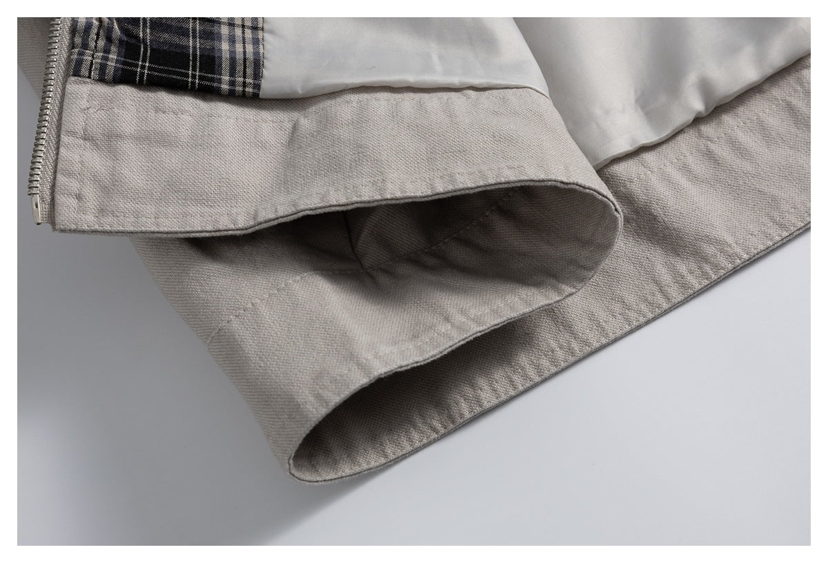 Close-up of the light gray jacket hem, showing the lining, plaid trim, and edge of the zipper.