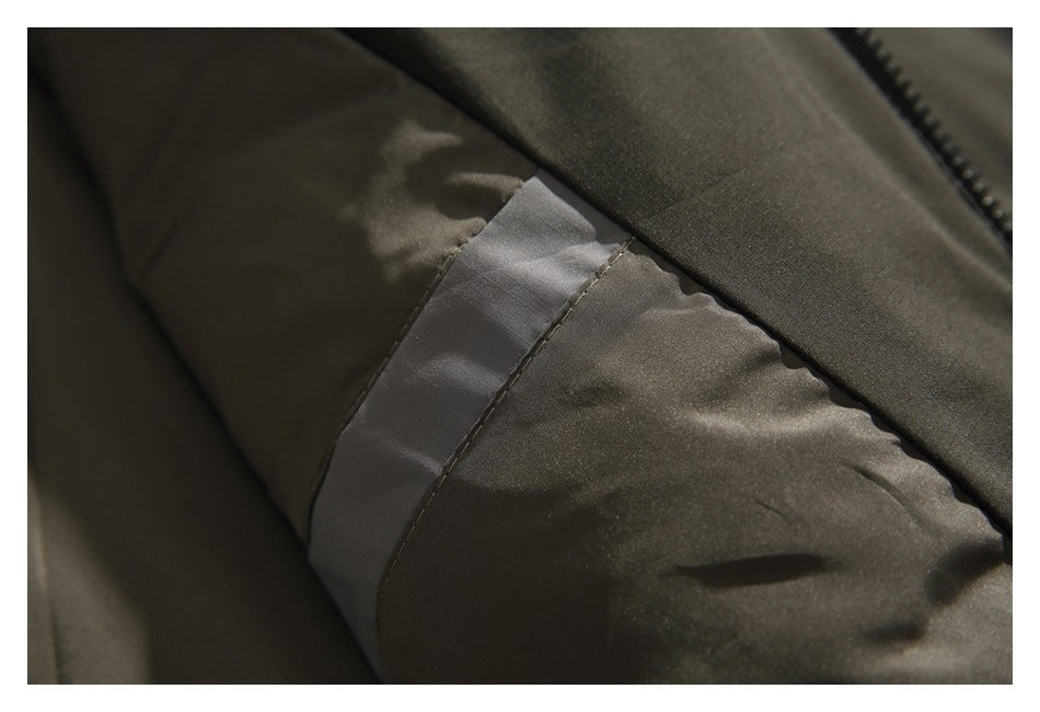 Close-up of an olive jacket sleeve showing a gray fabric panel and stitched seam.