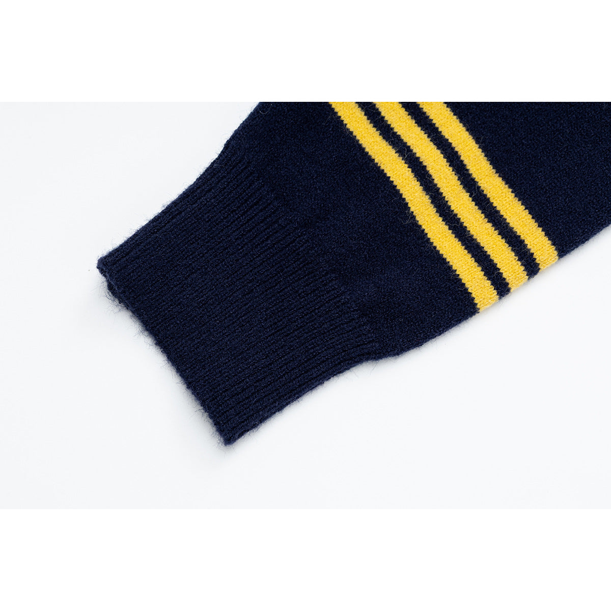 Close-up of a navy sweater sleeve cuff with three yellow stripes.