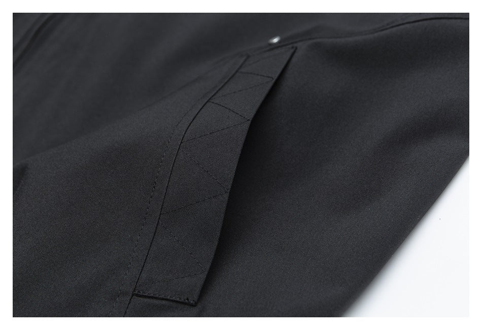 Close-up of black garment fabric with a stitched panel and diagonal seam detail.